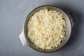 The cabbage is chopped and cooked for pickling in a bowl on a gray background.