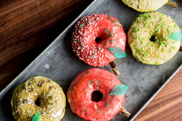 Doughnuts or donuts. Classic American favorite, apple cider donuts iced with maple syrup flavored butter cream frosting and topped with gold leaf sprinkles and decorations.