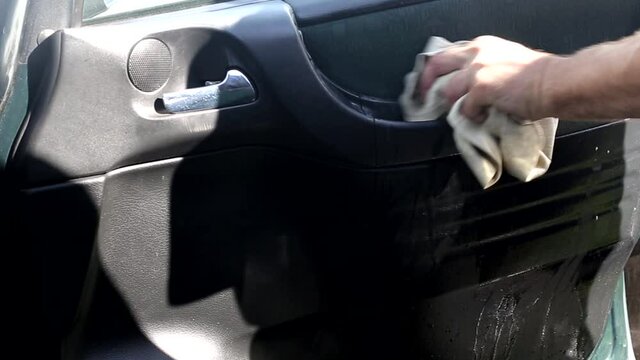 Man washes and cleans the upholstery on the car door, dry cleaning the car, interior