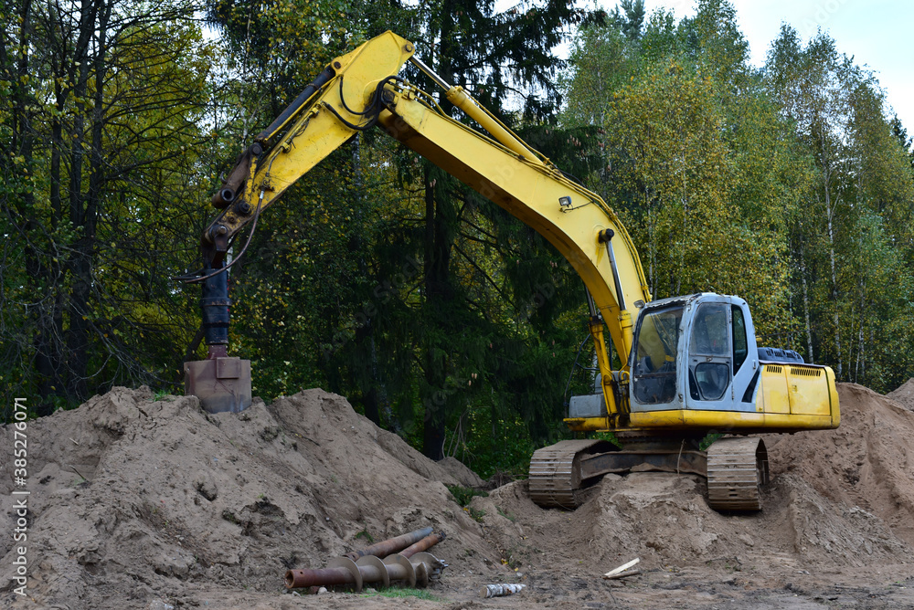 Poster Excavator with Vertical tamrock pile foundation drilling machine. Drill rig at forest area. Ground Improvement techniques, vibroflotation probe. Vibro compaction method. Piling Contractors