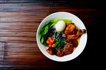 Ramen noodles. Japanese classic soup, with noodles, broth, pork, chicken, tofu, scallions, mushrooms, eggs and red pepper sauce. Copy space.
