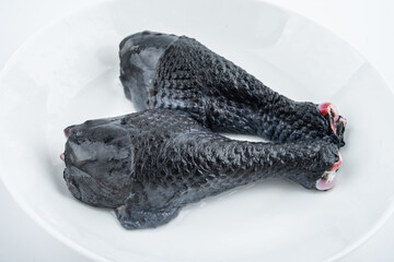 Two fresh black chicken drumsticks on white background