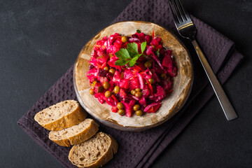 Vegetarian vegetable vinigret in a round clay plate on a dark background with copy space