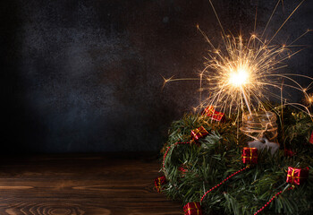 a wreath of fir branches and a sparkler on a dark background