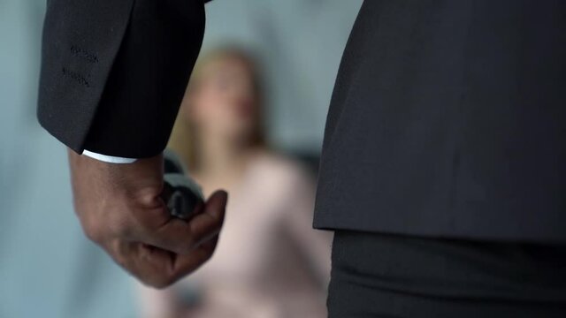 close-up of a male hand with dark skin. the man is fingering metal balls. in the background you can see a female figure in a light dress out of focus