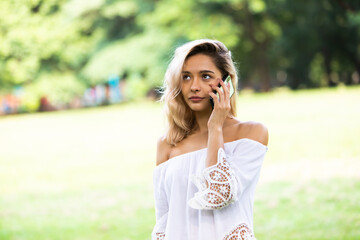 Young beautiful woman in park talking on cell phone.