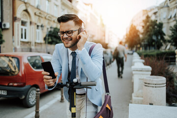 Young modern man using and driving electric scooter on city street and listens to music. Modern and ecological transportation concept.