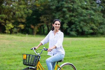 Young beautiful woman on yellow classic bicycle in green park.