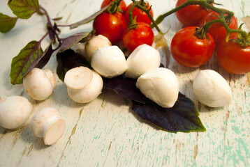 
Caprese salad ingredients. Basil, matsarella and cherry tomatoes on an old wood background.