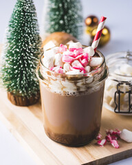 Glass Jar of Tasty Hot Cocoa or Chocolate Decorated with Marshmallow and Crumbled Candy Cane Christmas Beverage Blue Background Vertical