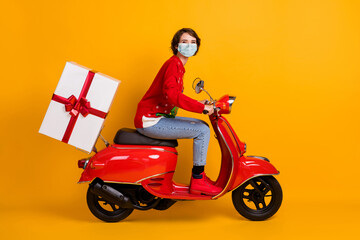 Fototapeta premium Full length profile photo of positive girl drive red motor bike deliver x-mas gift box wear mask jumper isolated color background