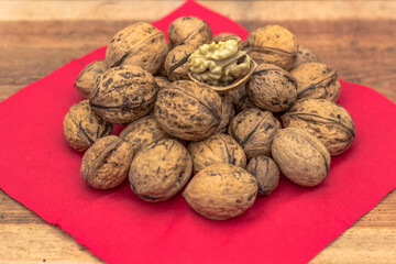 Closeup of big shelled walnuts pile. Walnut kernels and whole walnuts top view. Fresh raw walnuts full of healthy fats, fiber, vitamins and minerals.Eating walnuts to better brain function.Food scene.