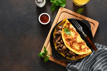 Omelet with mushrooms for breakfast with orange juice on the kitchen table.