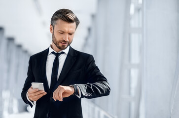 Handsome bearded businessman checking time while waiting for flight