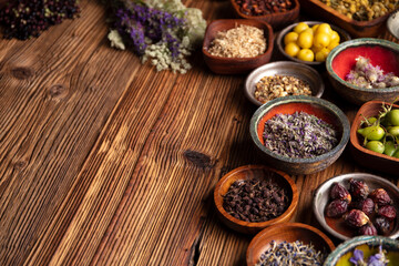 Obraz na płótnie Canvas Natural medicine theme. Assorted dry herbs in bowls and brass mortar on rustic wooden table.