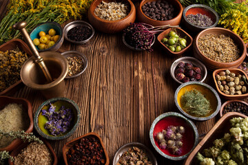 Natural medicine theme. Assorted dry herbs in bowls and brass mortar on rustic wooden table.