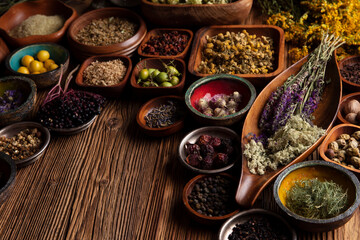 Natural medicine theme. Assorted dry herbs in bowls and brass mortar on rustic wooden table.