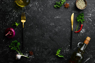 Kitchen banner: Spices, vegetables and cutlery on a black stone background. Top view. Free space...