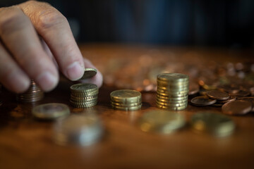 Hand und Geld, Mann zählt zuhause sein Kleingeld und baut Türme mit den Münzen