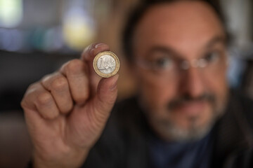 Mann hält eine Euromünze in der Hand, Euro