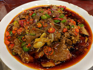 fresh braised beef with green and red peppers in the spicy soup in the white plate