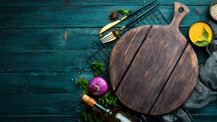 Culinary banner: Spices, vegetables and cutlery on a blue wooden background. Top view. Free space...