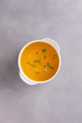 Bouillon with herbs in bowl on gray background