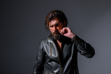 Brutal bearded biker. Handsome man in leather jacket. Barber Shop. Fashion. Trendy clothes. Bearded man in black jacket. Leather jacket. Pensive man in leather jacket.