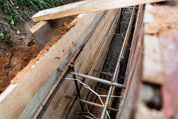 Timber formwork with metal reinforcement for pouring concrete and creating a solid foundation for a building or fence. Construction process