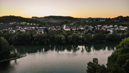 Fototapeta na wymiar Aerial view over Aare river, to the church and residential area of Umiken and Riniken, Switzerland at sunset.