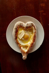 Caucasian cuisine khachapuri with egg and cheese. A melted piece of butter. Khachapuri in the shape of a heart