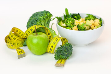  plate of green salad, a green apple with a centimeter tape. Fresh, organic food for a healthy lifestyle, weight loss