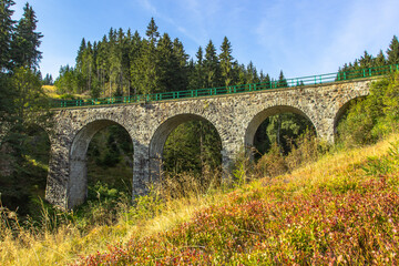 Fototapeta na wymiar View of stone Railway Viaduct in a small village of Pernink, Czech republic. Old Czech railway line. Vintage arch bridge.