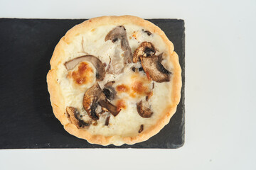 Tart with mushrooms and cheese on a white plate. Close-up