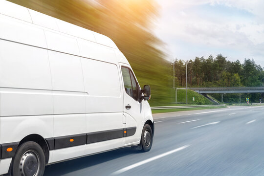 White modern delivery small shipment cargo courier van moving fast on motorway road to city urban suburb. Busines distribution and logistics express service. Mini bus driving on highway on sunny day