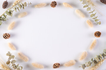 Autumn, fall concept. Frame made of eucalyptus branches, dried leaves on white background. Flat lay, top view, copy space