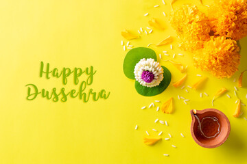 Clay Diya lamps lit during Dussehra with yellow flowers, green leaf and rice on yellow background....