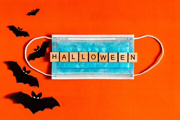 lettering Halloween on a medical protective mask on a black background with silhouettes of bats made of black paper, Halloween 2020 in a new reality. flat layout. Flat lay for your design