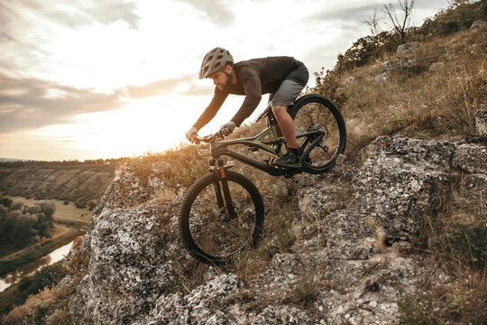 Man riding bike on rocky slope at sunset