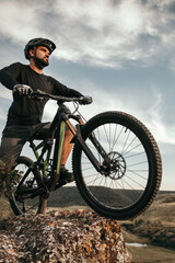 Fototapeta na wymiar Bearded cyclist with bike on rock in nature
