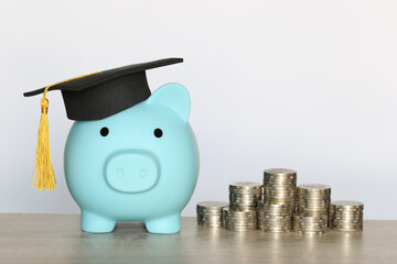 Graduation hat on blue piggy bank with stack of coins money on white background, Saving money for education concept