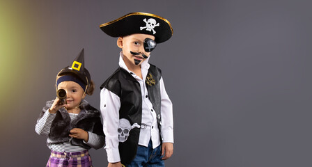 Happy friends, pirat boy and witch little girl at Halloween. Funny kids in carnival costumes on...