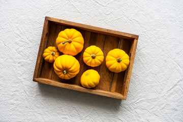 Kleine gelbe Kürbisse auf einem Holz Tablett. Draufsicht, beiges Leinen Tischtuch, Herbst,...