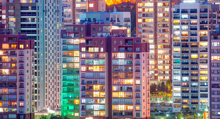 Fototapeta na wymiar Night view of exterior apartment colorful building. High rise skyscraper with lights in windows 