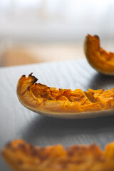 Roasted pumpkin slices. Freshly baked and juicy slices of pumpkin on the black table. Autumn flavors. Simple food concept. Baked in the oven. Healthy vegetarian food. 