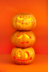 Three halloween pumpkins one on top of the other. Sad, crazy and evil face on orange background