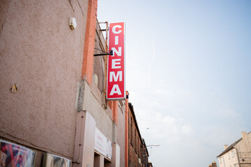 Obraz premium Cinema Signboard Hanging Outside a Brown Building Under a Bright Blue Sky