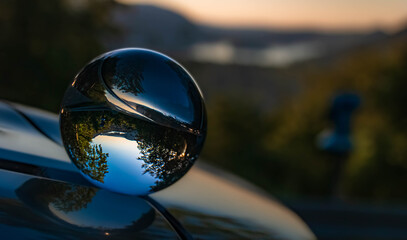 Crystal ball alpine sunset shot with reflections on a car roof at the famous Spitzingsee, Bavaria, Germany