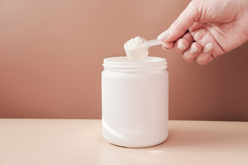 hand holding scoop of fish collagen. collagen peptides in container or jar. powder for mixing drink. Healthcare supplement concept. collagen for skin and joints .