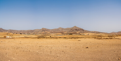 Fototapeta na wymiar Panoramic view of a desert landscape somewhere in the central part of the Fuerteventura. Canary Islands. Spain.